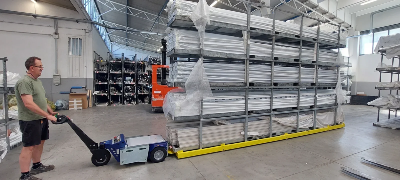 Zallys M6.5 electric tug towing long aluminum profiles in a warehouse setting