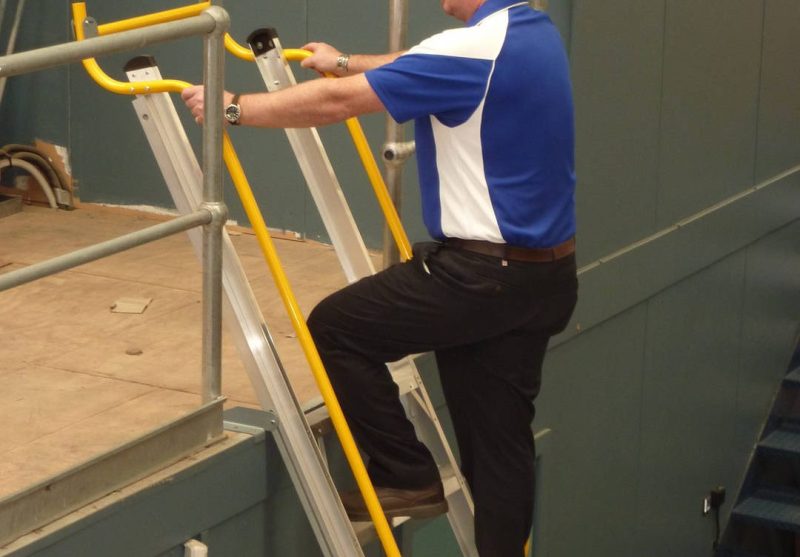 Worker using a mobile platform ladder for fall prevention in Australian workplaces.