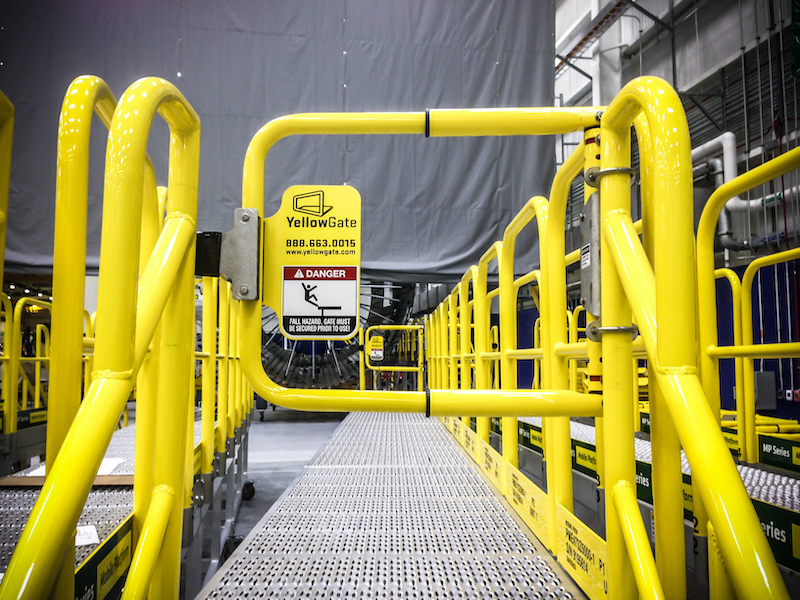 YellowGate Adjustable Safety Swing Gate in a warehouse aisle